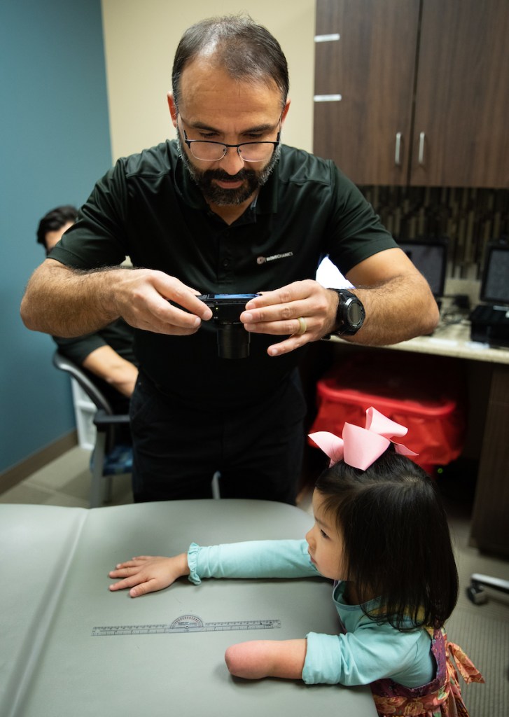 Jorge Zuniga takes photos of a child's limb differences to prepare a design for a 3D printed prosthetic arm for her.