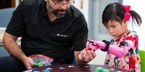Jorge Zuniga helps a young girl with a 3D printed prosthetic