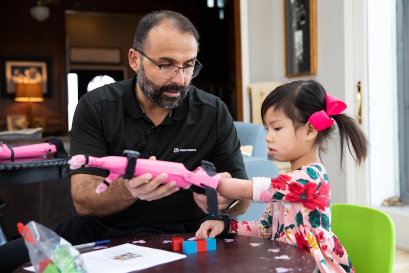 Jorge Zuniga fits a 3D printed prosthetic arm to a young girl during a research study in Nebraska