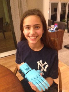 A girl scout holding a 3D printed e-NABLE hand that she assembled