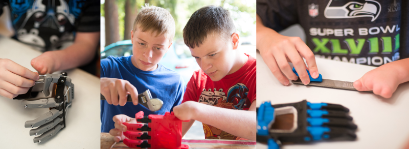 A limb different child assembles his own 3D printed e-NABLE hand with his brother